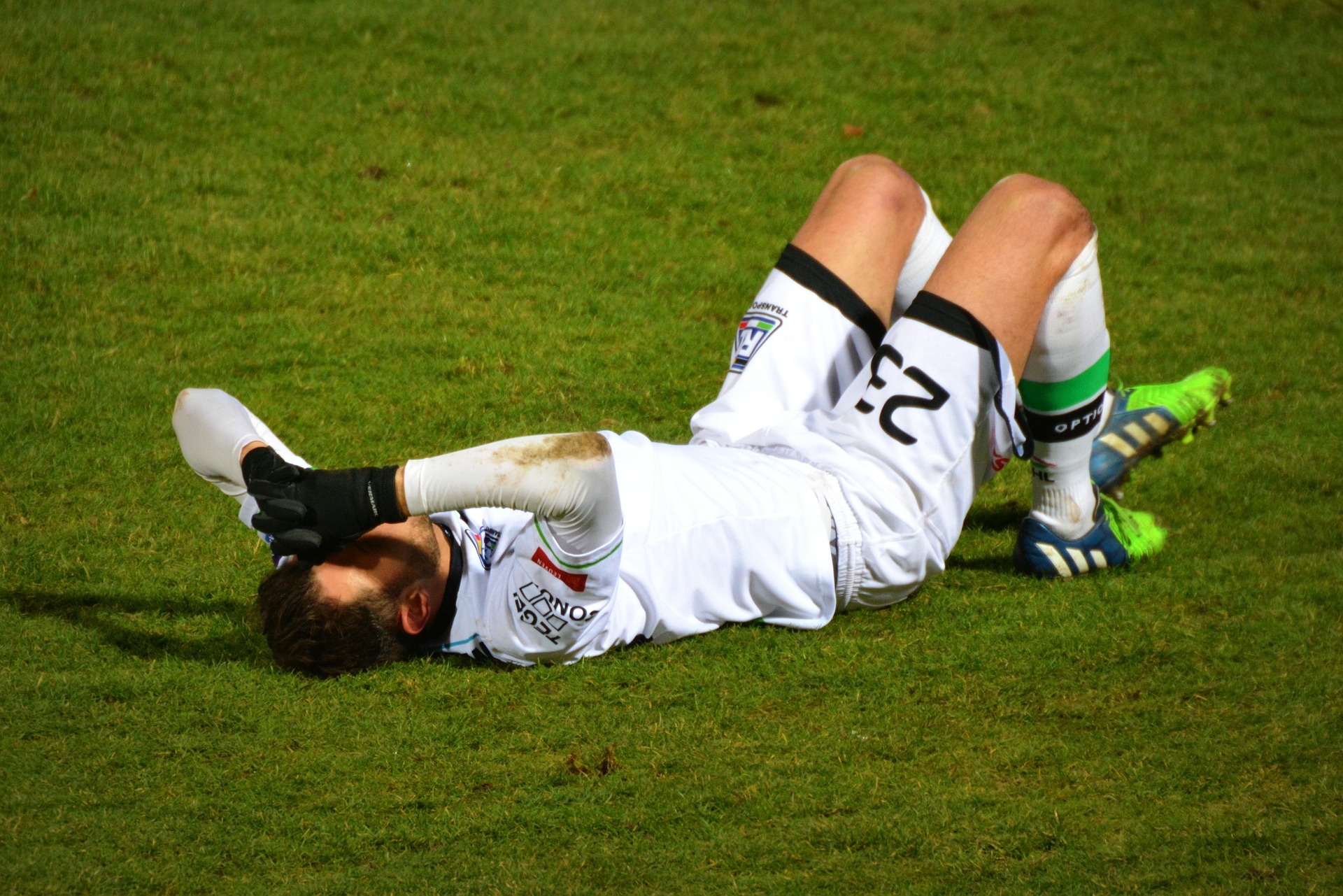 Fotbalista leží na trávě a drží se za nohu